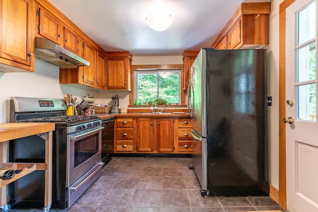 kitchen featuring appliances with stainless steel finishes, a sink, brown cabinets, and under cabinet range hood