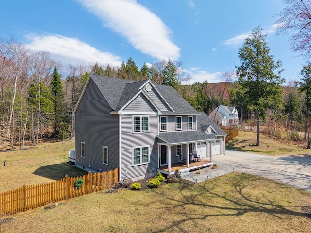 back of house featuring fence, covered porch, concrete driveway, and a lawn