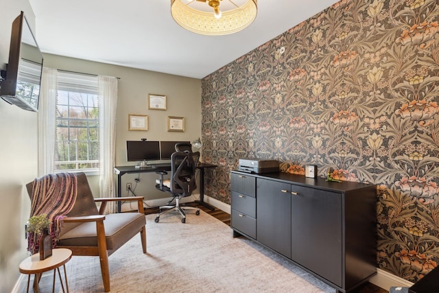 office area featuring an accent wall, wallpapered walls, wood finished floors, and baseboards