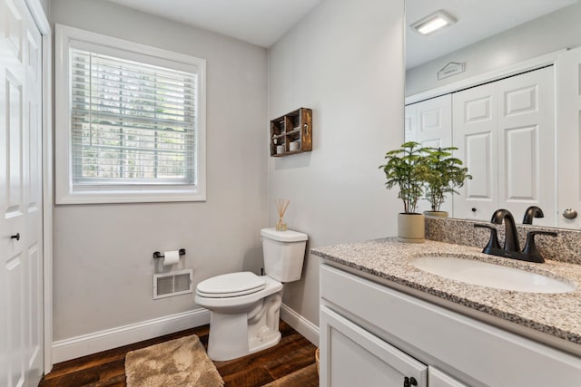 bathroom with visible vents, baseboards, toilet, wood finished floors, and vanity