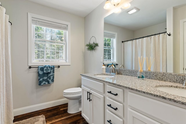 bathroom with baseboards, wood finished floors, toilet, and a sink