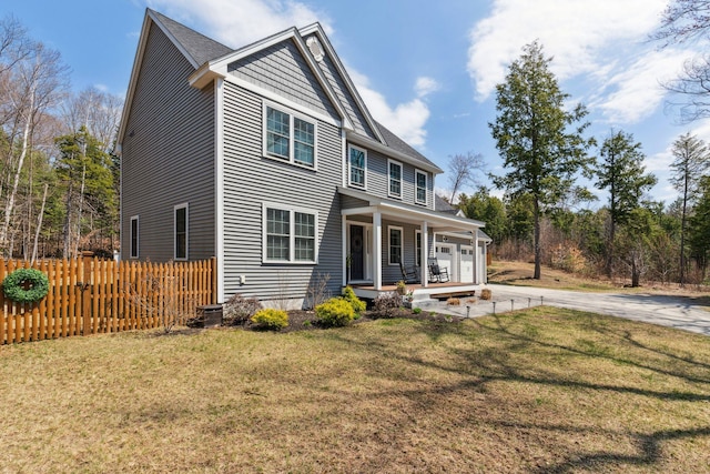 back of property with a porch, driveway, a yard, and fence