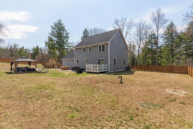back of property featuring a wooden deck, a gazebo, roof with shingles, a lawn, and a fenced backyard
