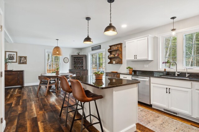 kitchen featuring a sink, visible vents, dishwasher, and dark wood-type flooring