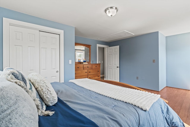 bedroom featuring attic access, wood finished floors, and a closet