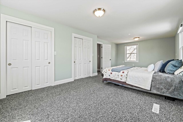 bedroom with baseboards, carpet floors, and two closets