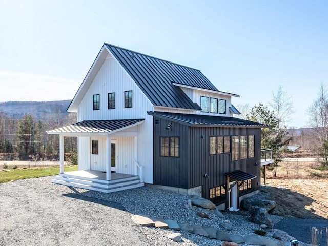 back of property with metal roof, a standing seam roof, and a porch