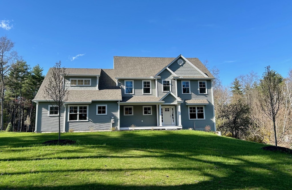 view of front of home featuring roof with shingles and a front lawn