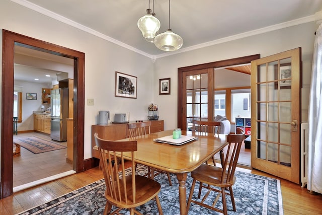 dining space with baseboards, light wood-type flooring, and ornamental molding