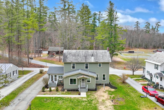 view of front facade with driveway, roof with shingles, a front yard, and entry steps