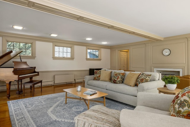living area featuring crown molding, wood finished floors, and a decorative wall