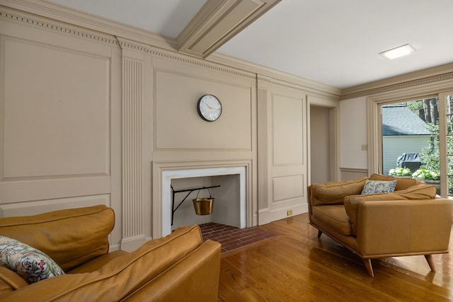 living room with wood finished floors, a decorative wall, and crown molding