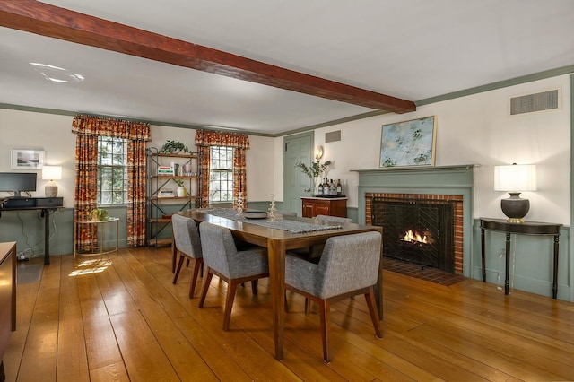 dining room with a fireplace, beam ceiling, visible vents, and hardwood / wood-style floors