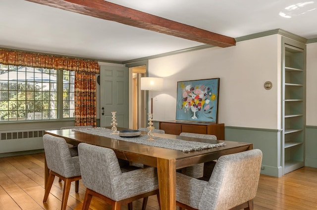 dining room with light wood-style floors, beamed ceiling, and radiator