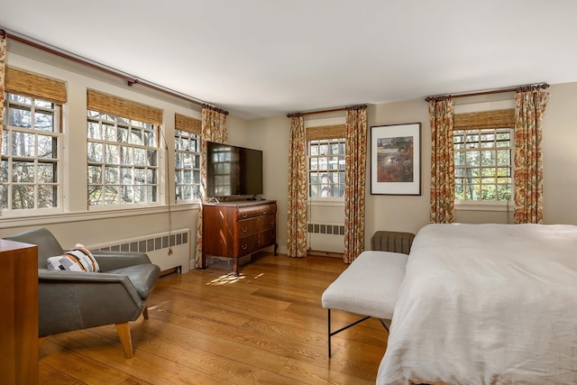 bedroom with multiple windows, wood finished floors, and radiator