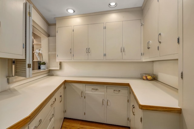 kitchen featuring light wood-style floors, light countertops, crown molding, and recessed lighting