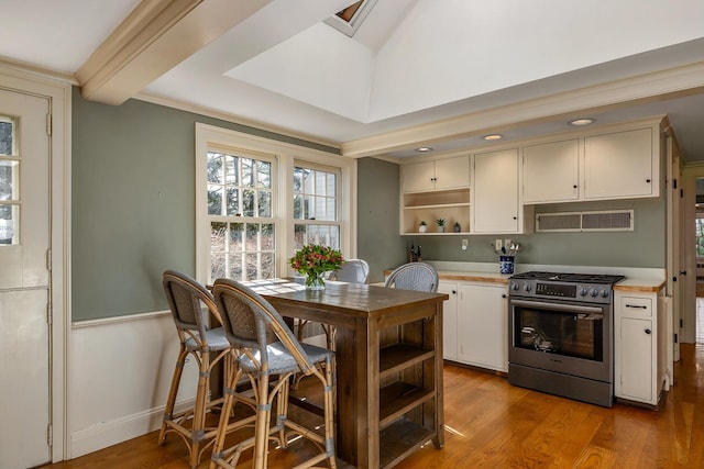 kitchen with range hood, open shelves, light countertops, gas stove, and wood finished floors