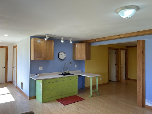 kitchen featuring a sink, visible vents, light countertops, baseboards, and light wood-type flooring