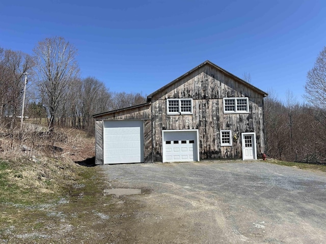 view of side of home featuring an outbuilding, a detached garage, dirt driveway, and a barn
