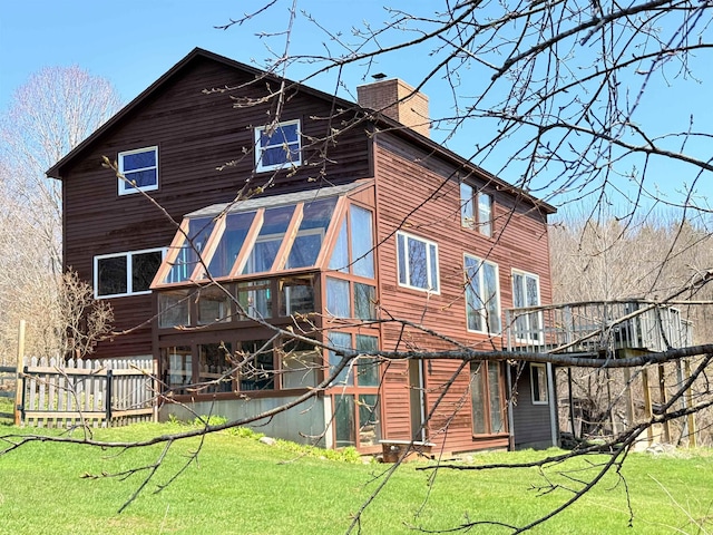 back of house with a lawn, a chimney, and a sunroom