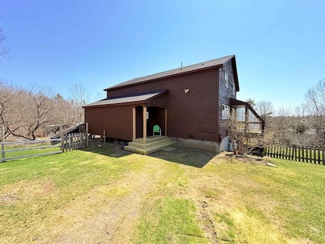 rear view of property featuring a yard and fence