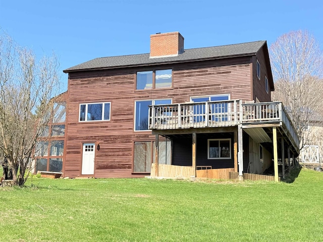 back of house with a wooden deck, a yard, roof with shingles, and a chimney