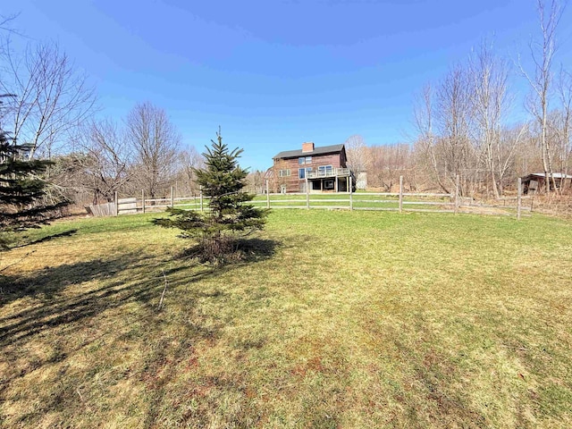 view of yard with fence and a rural view