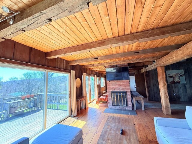 unfurnished living room featuring beamed ceiling, wooden walls, hardwood / wood-style flooring, and wood ceiling