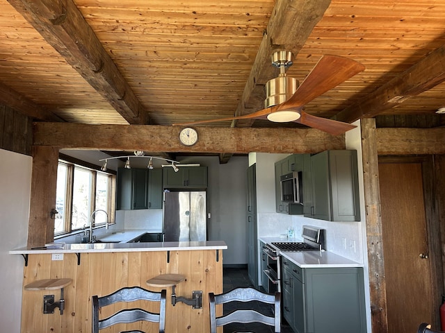 kitchen with beamed ceiling, a sink, appliances with stainless steel finishes, ceiling fan, and a peninsula