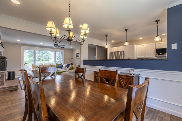 dining space with crown molding, ceiling fan with notable chandelier, dark wood-style floors, and recessed lighting