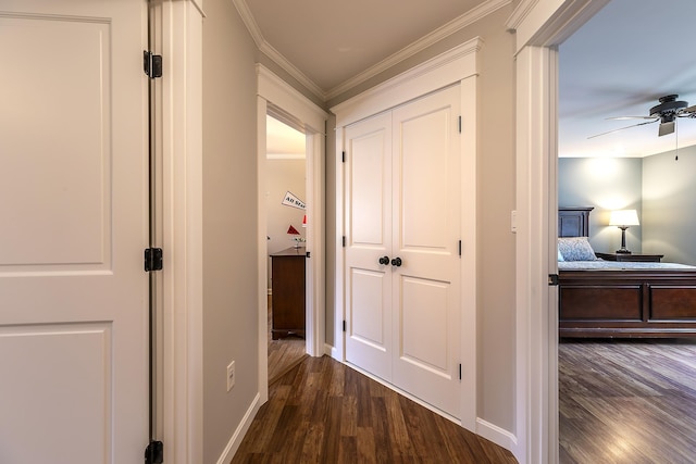 hall featuring crown molding, dark wood-style flooring, and baseboards