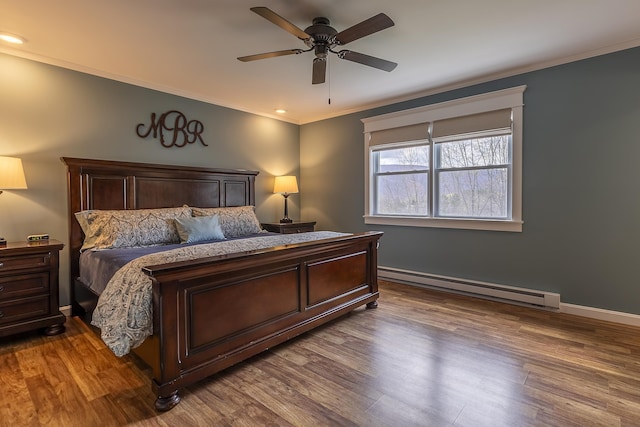 bedroom featuring crown molding, a ceiling fan, baseboards, baseboard heating, and wood finished floors