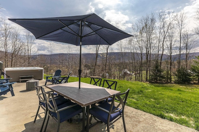 view of patio with a mountain view, outdoor dining area, and a hot tub