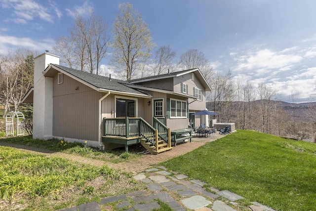 back of property featuring a chimney, a patio, a shingled roof, and a lawn