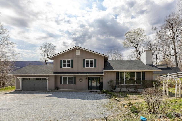 tri-level home with a porch, a garage, a shingled roof, a chimney, and gravel driveway