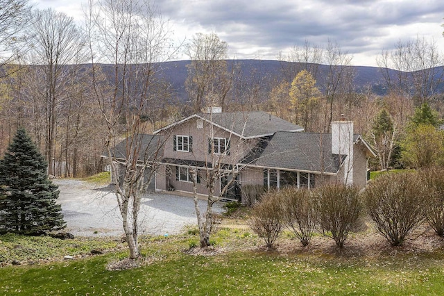 exterior space with a chimney, dirt driveway, and a forest view