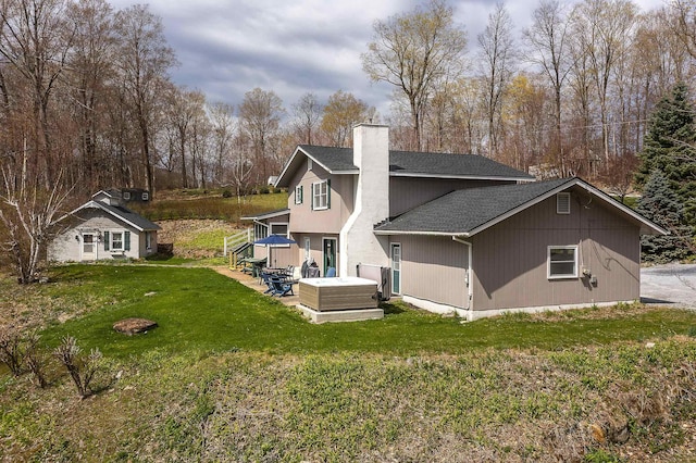 back of property featuring roof with shingles, a chimney, a yard, and a patio area