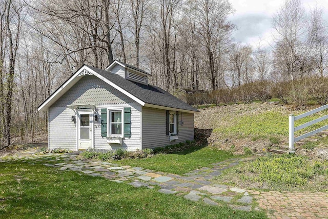 view of front of home featuring a front lawn and roof with shingles