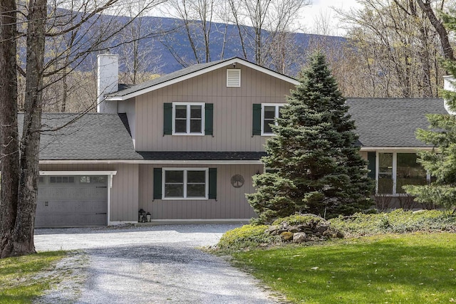 view of front of house featuring a chimney, a shingled roof, a garage, driveway, and a mountain view