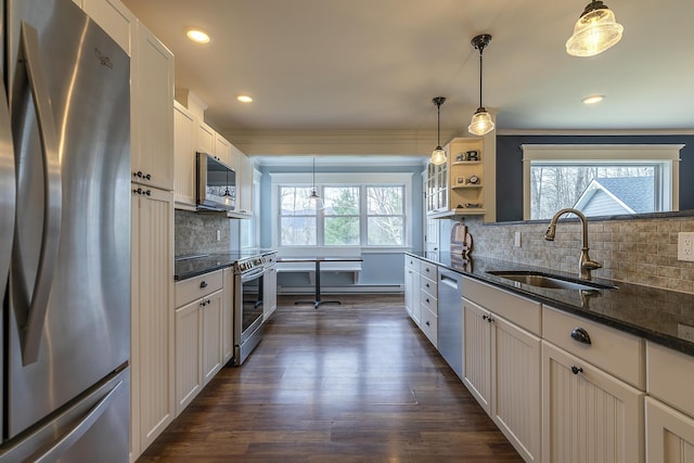 kitchen featuring dark wood finished floors, decorative backsplash, stainless steel appliances, ornamental molding, and a sink