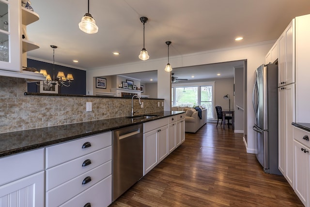 kitchen with decorative backsplash, stainless steel appliances, a sink, white cabinetry, and open floor plan