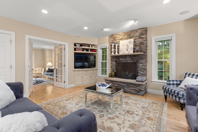 living room featuring baseboards, recessed lighting, wood finished floors, and a stone fireplace