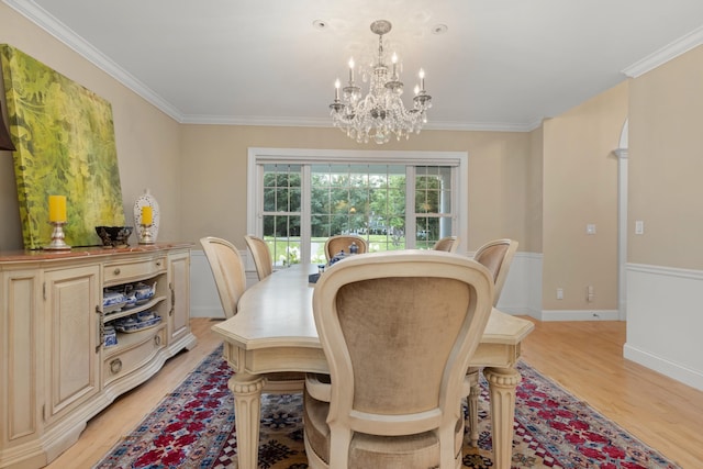 dining room with an inviting chandelier, ornamental molding, light wood-style flooring, and baseboards