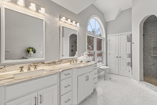 bathroom with a tile shower, a sink, and a wealth of natural light