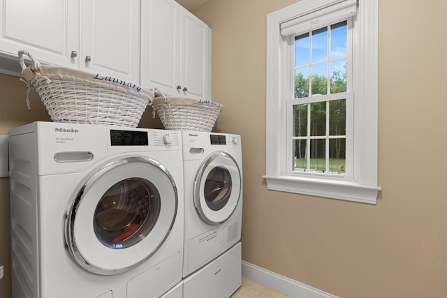 laundry room with cabinet space, baseboards, and washer and clothes dryer