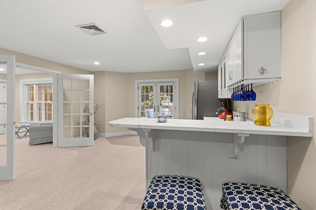 kitchen featuring visible vents, freestanding refrigerator, recessed lighting, french doors, and a peninsula
