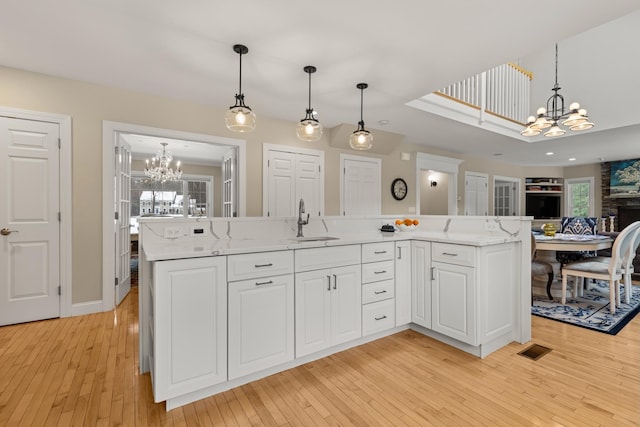 kitchen featuring white cabinetry, a sink, a chandelier, visible vents, and open floor plan