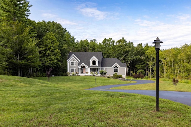 view of front of house with a wooded view and a front yard