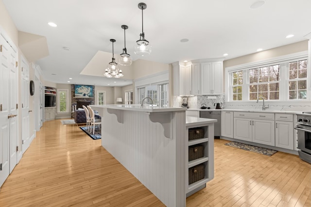 kitchen featuring tasteful backsplash, light wood-style flooring, appliances with stainless steel finishes, light countertops, and open floor plan