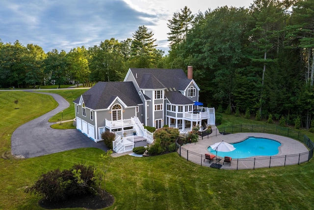 rear view of property featuring a chimney, a yard, stairs, and a fenced backyard